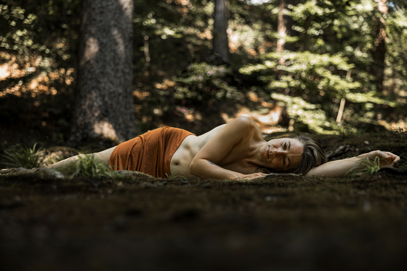 Frau liegt entspannt am Waldboden